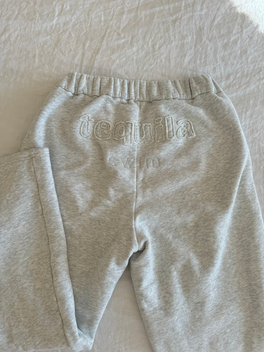 Light gray Bunny Sweatpants with elastic waistband and subtle embroidered "tequila swim" logo on back waistband