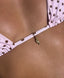 Close-up of light pink triangle bikini top with brown polka dots and gold hand charm detail on sun-kissed skin