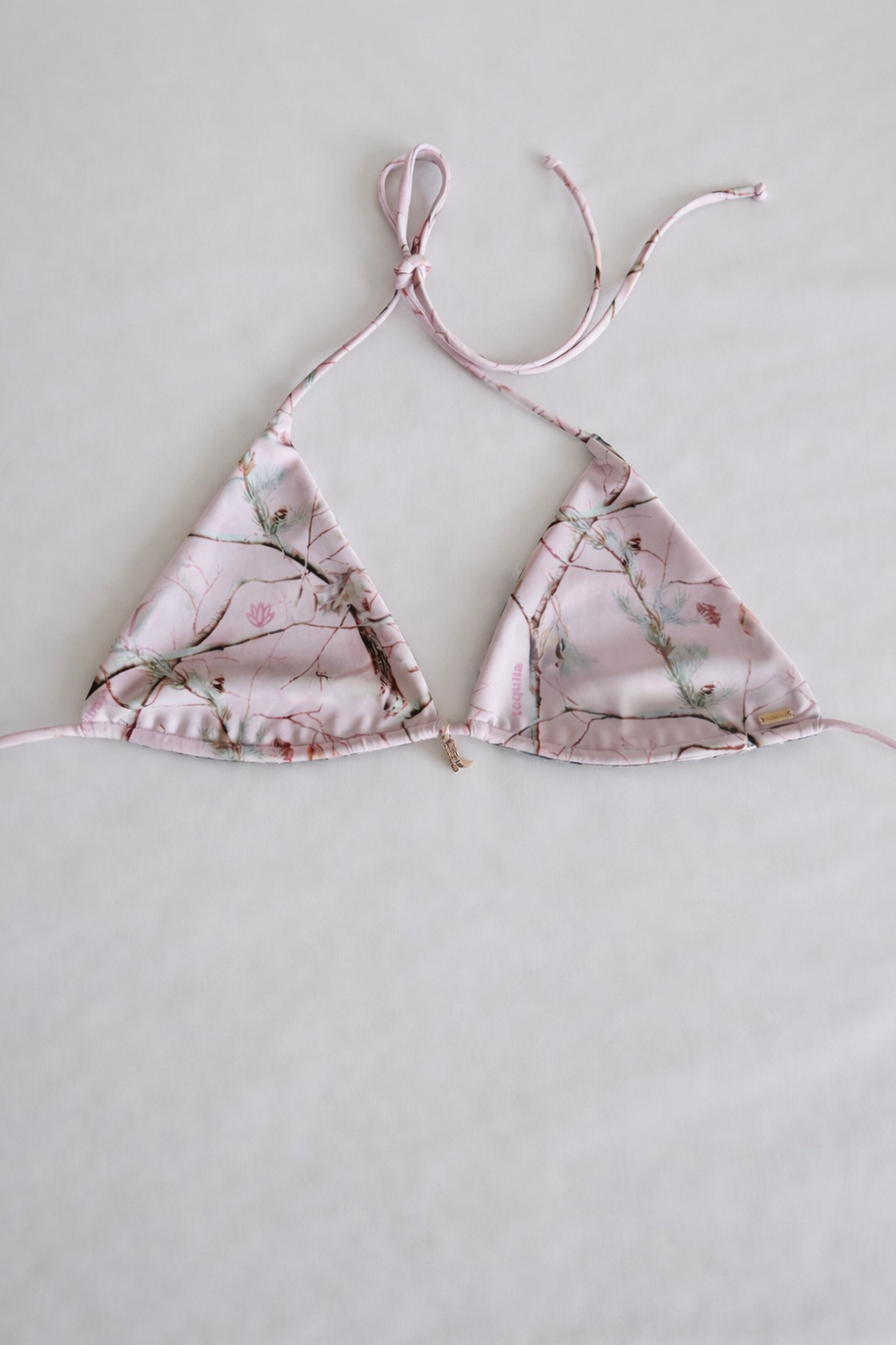 Pink floral reversible Leslie bikini top with adjustable ties and white lace trim, featuring a small cross charm detail.