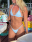 Woman wearing light blue polka dot triangle bikini top and thong bottoms at colorful outdoor ice cream parlor seating area