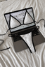 White triangle bikini set with black polka dots and black trim displayed on an open laptop keyboard