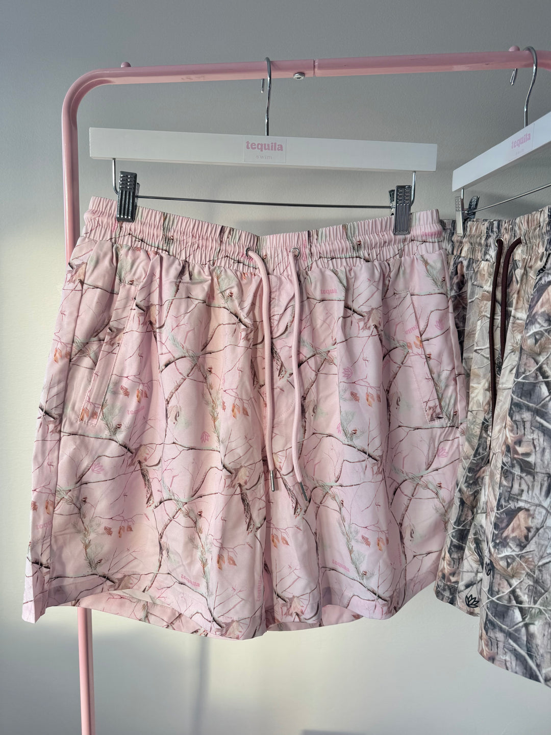 Pink camo Jaimo 5.5" shorts with stretch waistband and adjustable drawstrings hanging on rack.