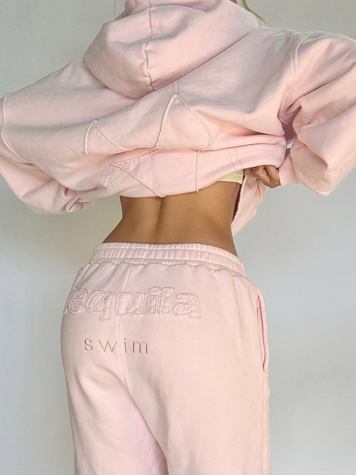 Back view of light pink Bunny Sweatpants with embroidered "Tequila swim" logo on the waistband worn with matching cropped hoodie