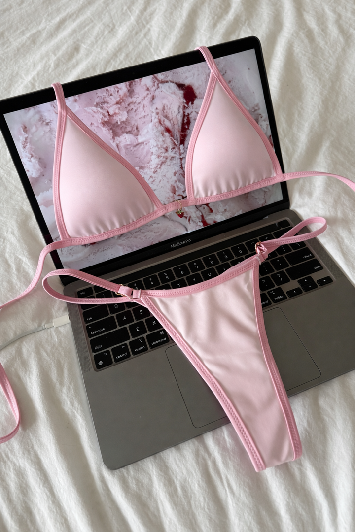 Pink bikini set on a laptop with a marble background