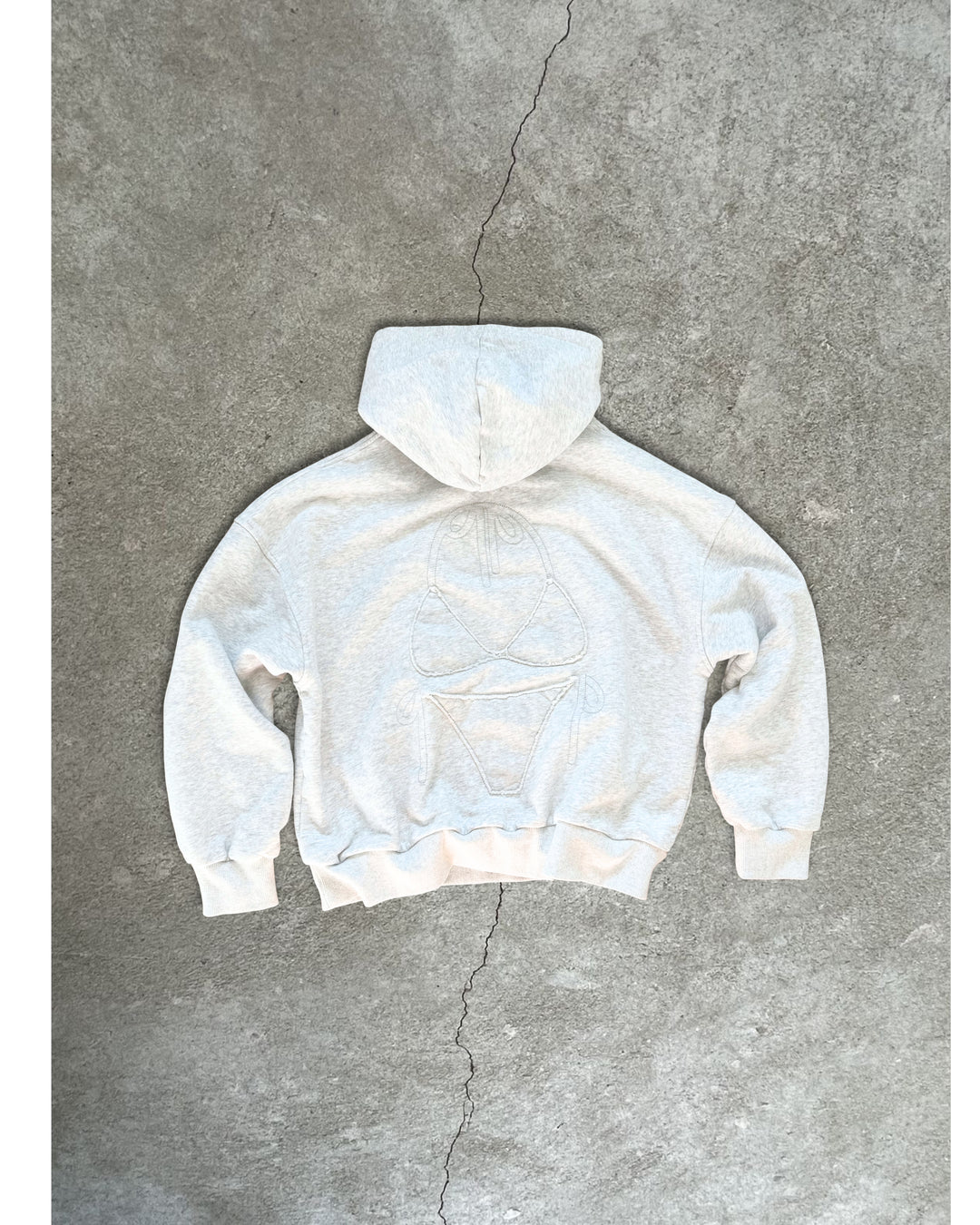 Light gray Bunny Hug Hoodie with subtle embroidered design, laid flat on concrete background showing back view.