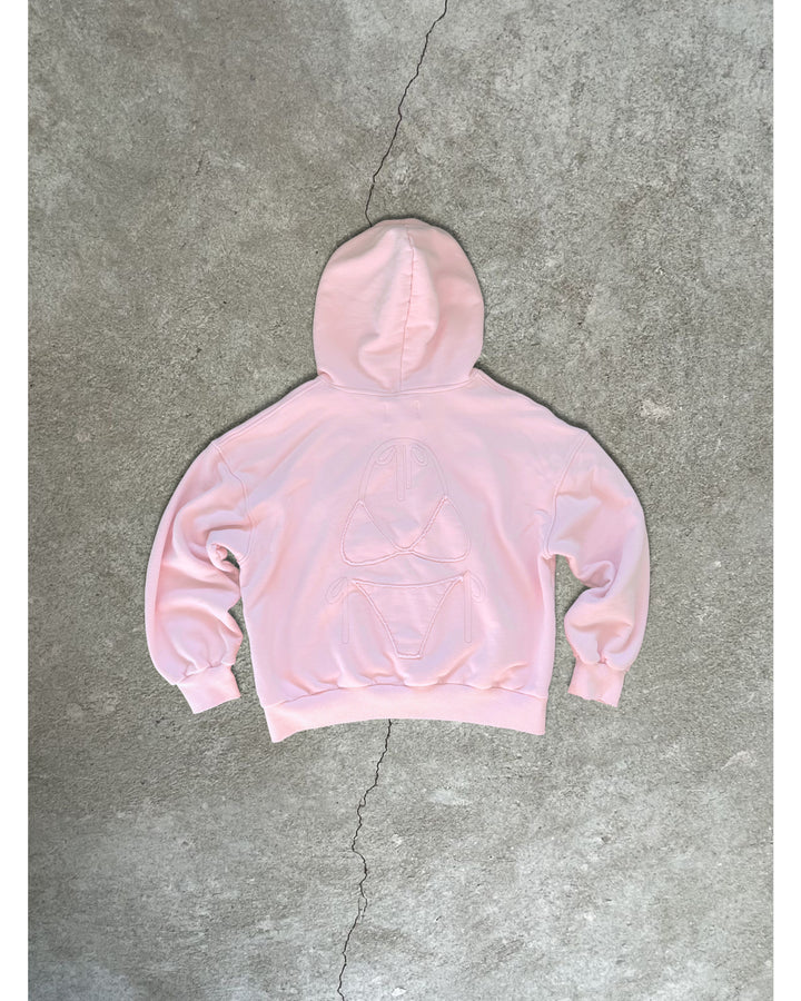 Light pink Bunny Hug Hoodie with embossed bunny design on the back laid flat on concrete floor background