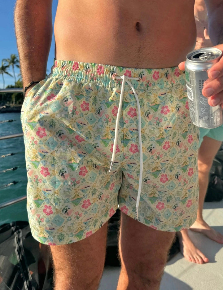Man wearing pastel floral swim shorts with elastic waistband and white drawstring holding a drink can on a boat