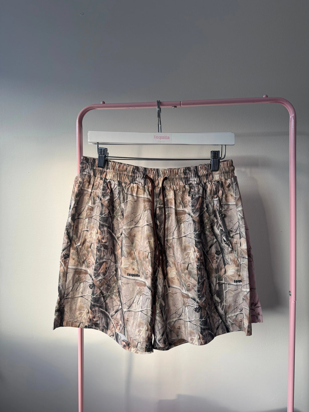 Jaimo 5.5 inch camo shorts hanging on pink rack with adjustable waistband and soft stretch fabric