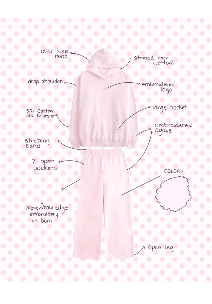 Light pink hoodie and pants set with embroidered logo, striped cotton liner, large pocket, and elastic waistband on polka dot background
